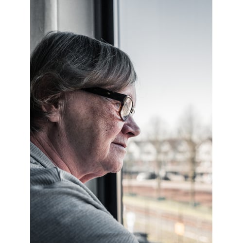 Dame op leeftijd die uit het raam kijkt